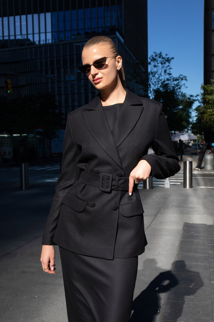 Close-up of fabric-covered buckle and structured lapels on black blazer by Anastasiia Ivanova