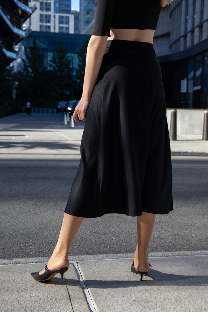 Back view of black midi skirt with waistband, zipper, and button closure