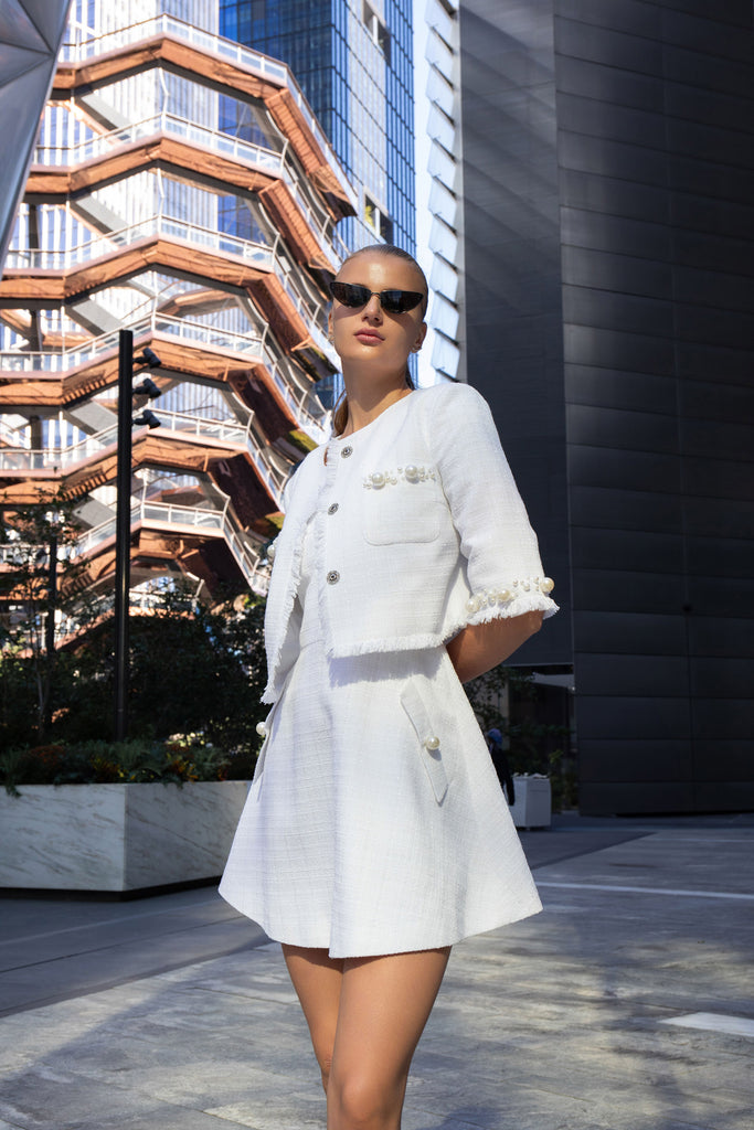 White tweed jacket with pearl embroidery draped over the shoulder of matching sundress by Anastasiia Ivanova, chic limited-edition look