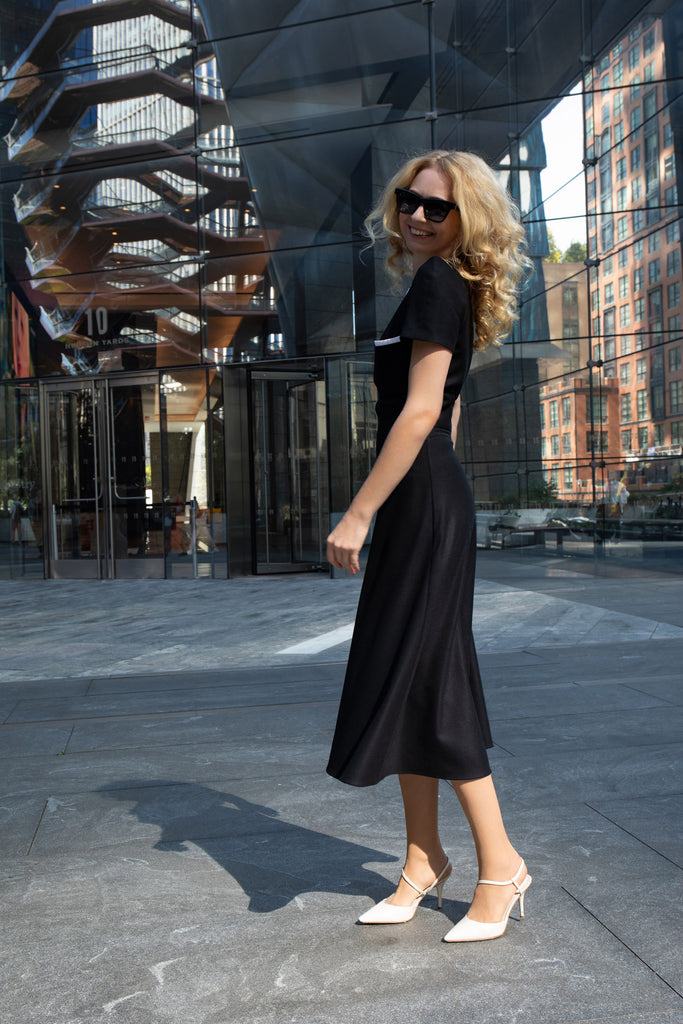 Back view showing concealed zipper and smooth silhouette of black midi dress.