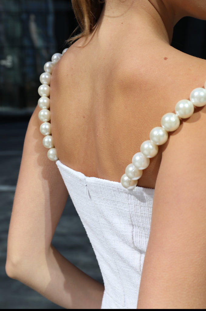 Detail of back pearl strap on white tweed sundress by Anastasiia Ivanova, elegant design element with modern femininity.