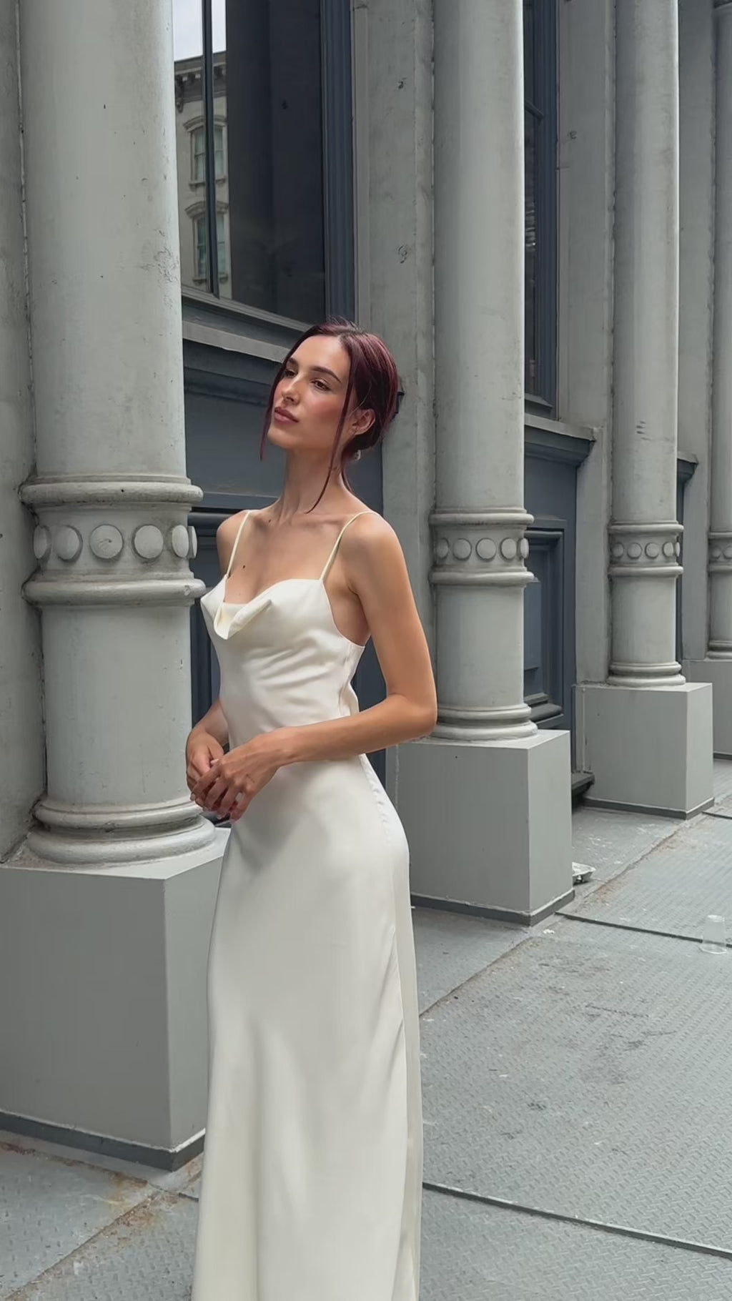 Lifestyle video of a modern bride walking through the city in an ivory silk maxi slip dress, highlighting the elegant drape and movement of the bias-cut fabric for a courthouse wedding