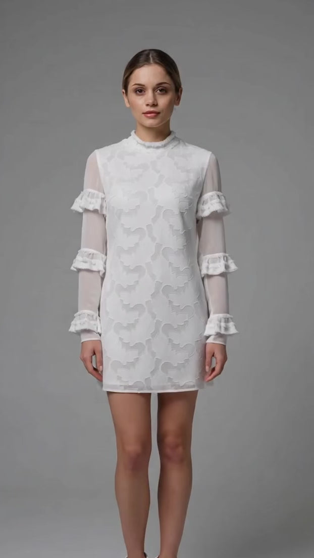 A detailed video demonstration of the textured white chiffon ruffle mini dress by Anastasiia Ivanova. The model poses from multiple angles, showcasing the sheer long sleeves with tiered ruffles, the elegant high neckline, and the intricate fabric texture. A perfect chic outfit for a bridal shower, rehearsal dinner, or modern civil wedding.