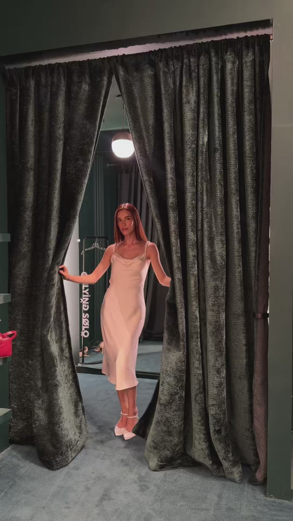 Bride trying on the luxury ivory double silk midi slip dress in front of a mirror, showcasing the flawless seams, adjustable silk strap, and elegant ceramic pearl details