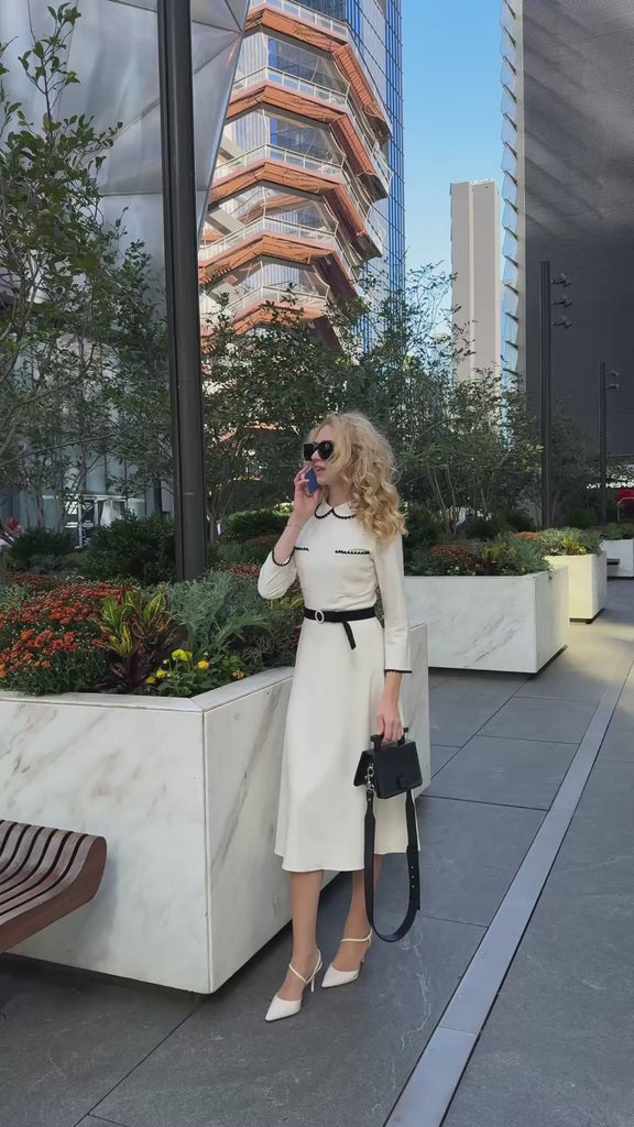 Video White dress with black trim by Anastasiia Ivanova styled in urban setting with architectural background.
